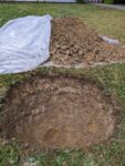 Tree hole dug to depth, with dirt pile nearby